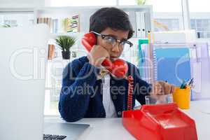 Boy pretending as businessman using land line phone
