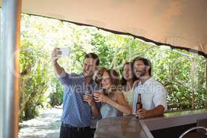 Friends taking selfie while having alcohol at counter