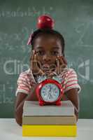 Schoolgirl sitting with red apple on her head against chalkboard