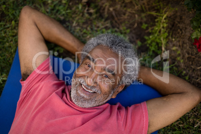 Portrait of smiling senior male resting while lying on exercise mat