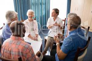 High angle view of smiling female doctor talking to seniors while sitting on chairs