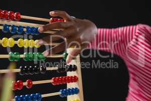 Schoolgirl using abacus against black background