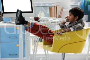 Businessman talking on phone while sitting with feet up