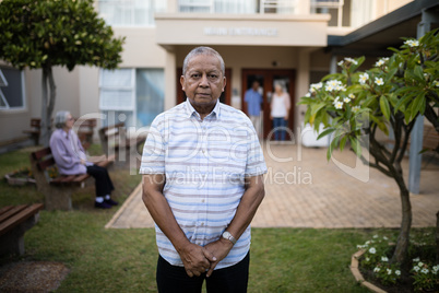 Portrait of senior man standing against friends