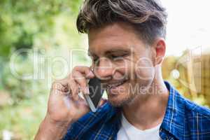 Man talking on mobile phone in garden on a sunny day