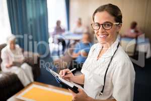 Portrait of smiling female doctor writing in file