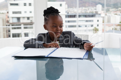 Smiling businesswoman with file and pen sitting at conference table