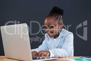 Smiling businesswoman wearing eyeglasses using laptop