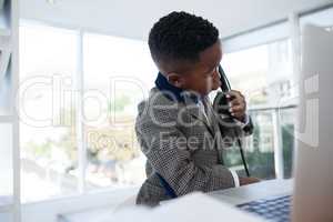 Businessman with laptop discussing on phone in office