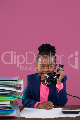 Smiling businesswoman talking on telephone while doing paperwork