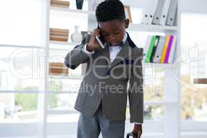 Businessman talking on mobile phone against shelf