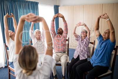 Female doctor stretching with seniors sitting on chairs