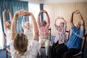 Female doctor stretching with seniors sitting on chairs