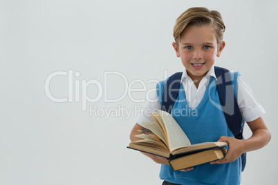 Portrait of happy schoolboy holding books against white background