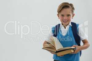 Portrait of happy schoolboy holding books against white background