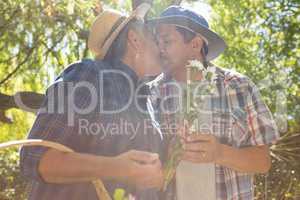 Senior couple kissing in garden with flower basket