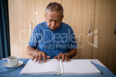 Senior man reading book at table