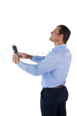 Side view of happy businessman looking up while using tablet computer