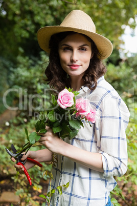 Woman trimming flowers with pruning shears in garden on a sunny day