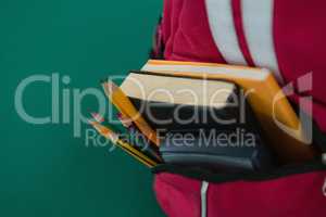 Schoolbag with various supplies on green background