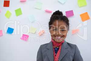 Portrait of smiling businesswoman standing  against sticky notes on wall