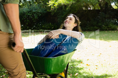 Man interacting with woman while pushing wheelbarrow in garden Man interacting with woman while pushing wheelbarrow in garden
