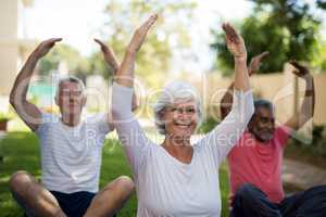 Smiling senior people exercising with arms raised