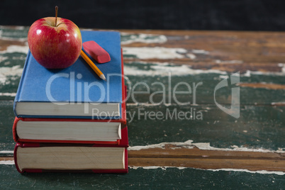 Apple, pencil and eraser on stack of books