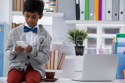 Businessman using smartphone while sitting on desk