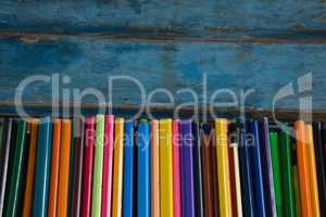Various color pencils arranged on wooden table
