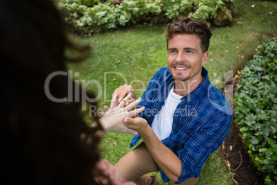 Handsome man wearing engagement ring to woman