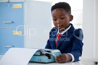 Boy imitating as businessman working on typewriter