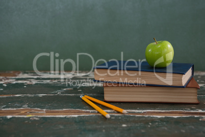 Apple on stack of books with pencils