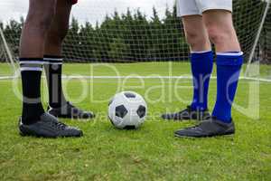 Low section of male soccer players with ball on field