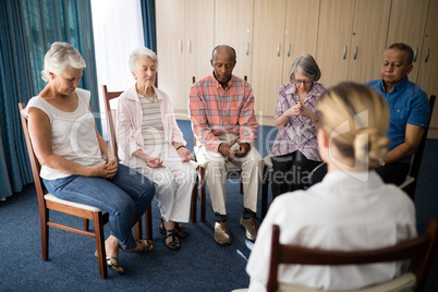 Senior people meditating with female doctor