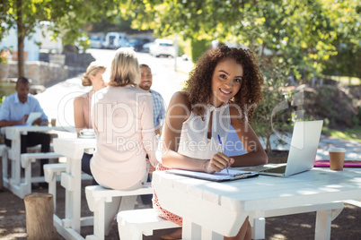 Smiling beautiful woman writing on clipboard in restaurant