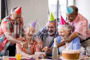 Cheerful senior people pointing at smart phone in party