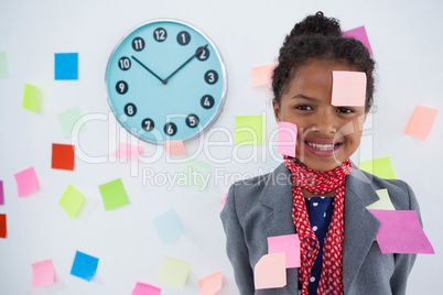 Happy businesswoman with adhesive notes stuck on suit and head