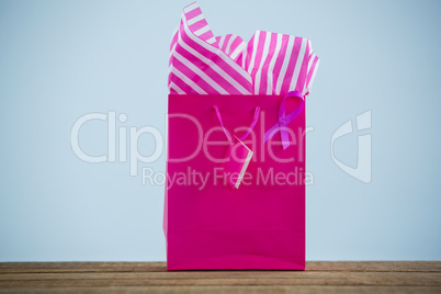 Close-up of vibrant pink Breast Cancer Awareness ribbon on shopping bag over wooden table