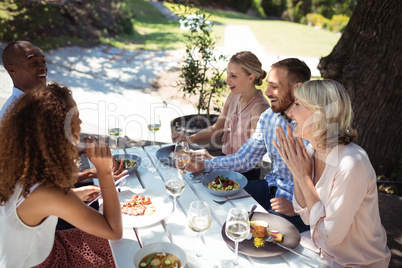 Happy friends interacting with each other while having meal