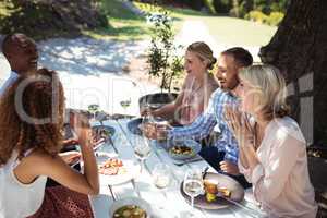 Happy friends interacting with each other while having meal