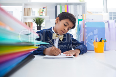 Boy imitating as businessman writing on paper