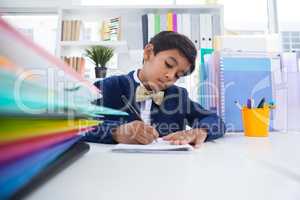 Boy imitating as businessman writing on paper