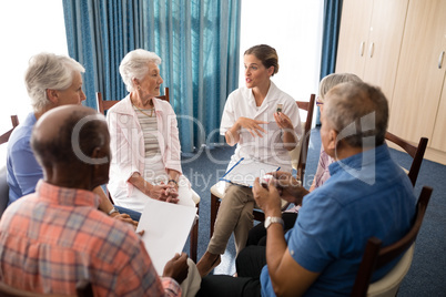 High angle view of female doctor talking to seniors while sitting on chairs