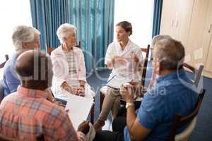 High angle view of female doctor talking to seniors while sitting on chairs