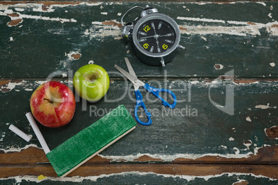 Apple, alarm clock, duster, scissors and chalk on wooden table