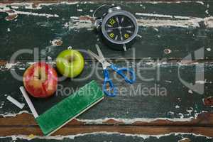 Apple, alarm clock, duster, scissors and chalk on wooden table