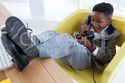 High angle view of happy boy imitating as businessman talking on landline phone