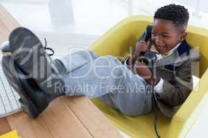 High angle view of happy boy imitating as businessman talking on landline phone