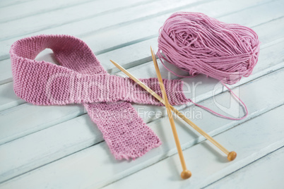 High angle view of pink woolen Breast Cancer Awareness ribbon with crochet needles on table